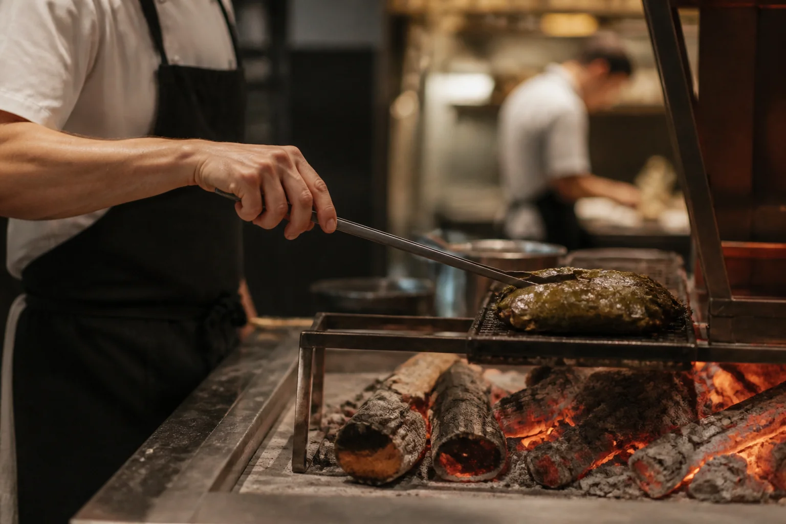 Mains d’un chef travaillant un légume au-dessus des braises